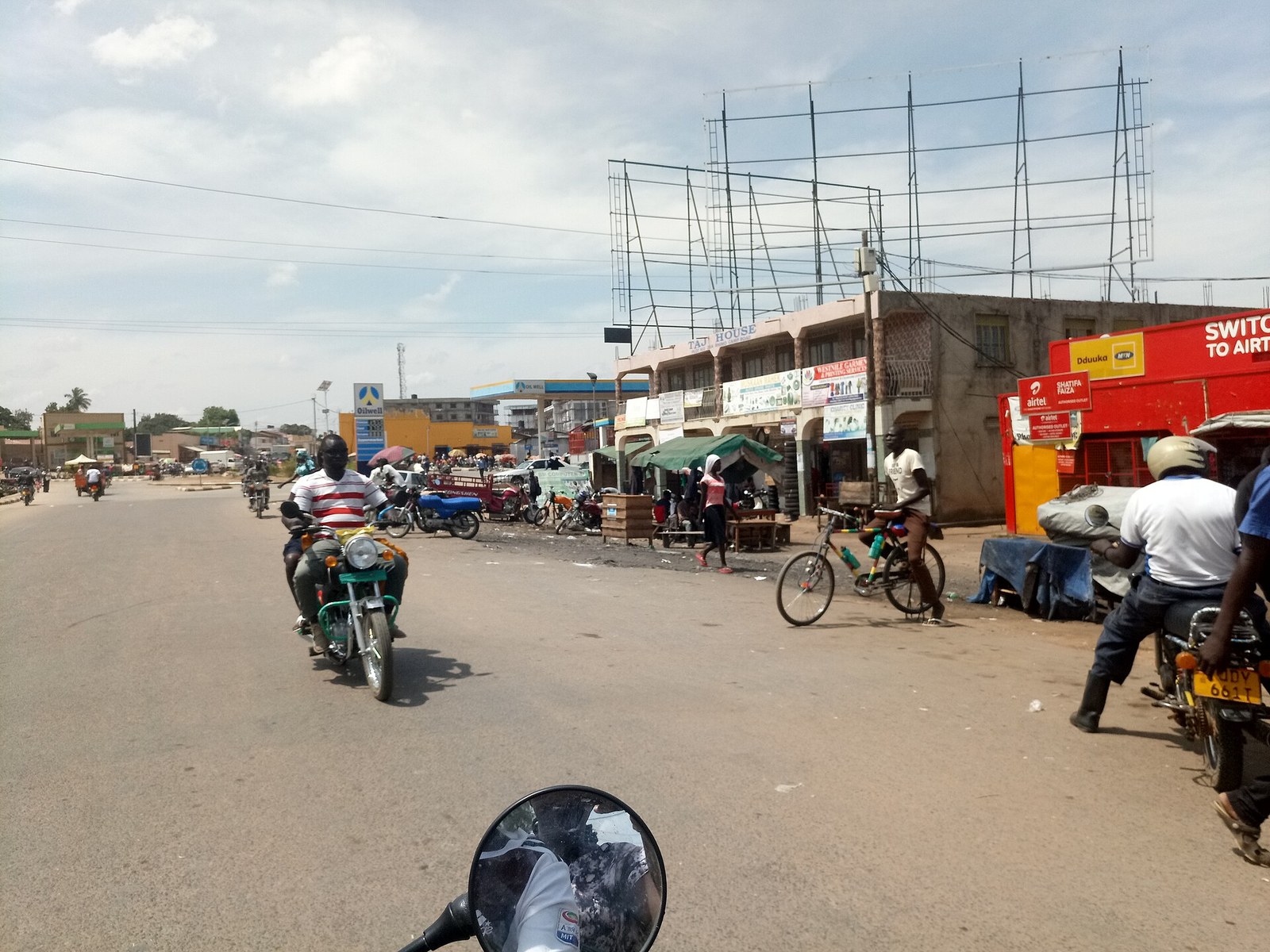 A busy Arua street from the saddle of a boda-boda — a parade of shopfronts with Airtel and