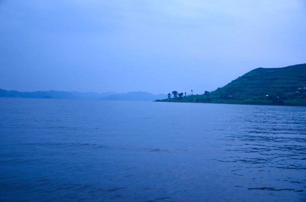 A terraced hill rising straight out of still lake water at dusk