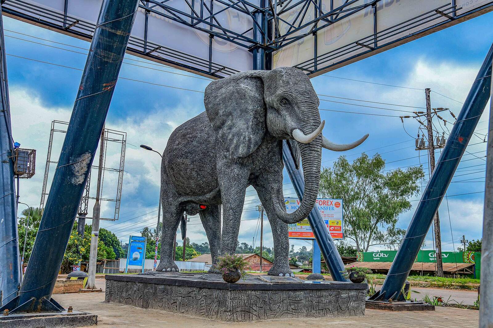 The life-size grey elephant statue on its carved plinth at the entrance to Gulu City, under a