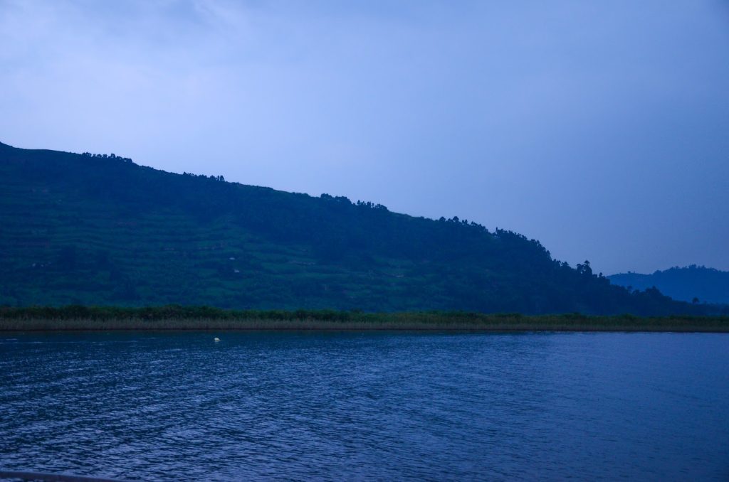 A long forested ridge running down to still blue lake water