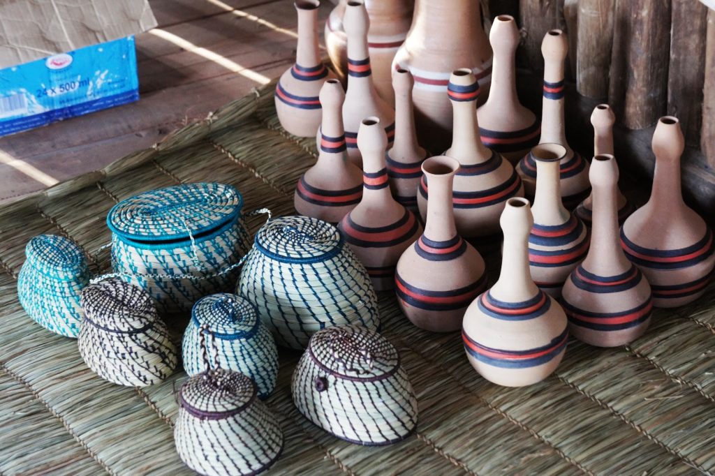 Woven baskets and turned clay vessels laid out on a mat at a craft stall